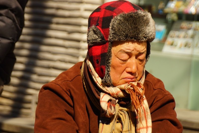 Korean man wearing a warm hat, scarf and jacket to brave the cold in Insadong, Seoul, Korea 