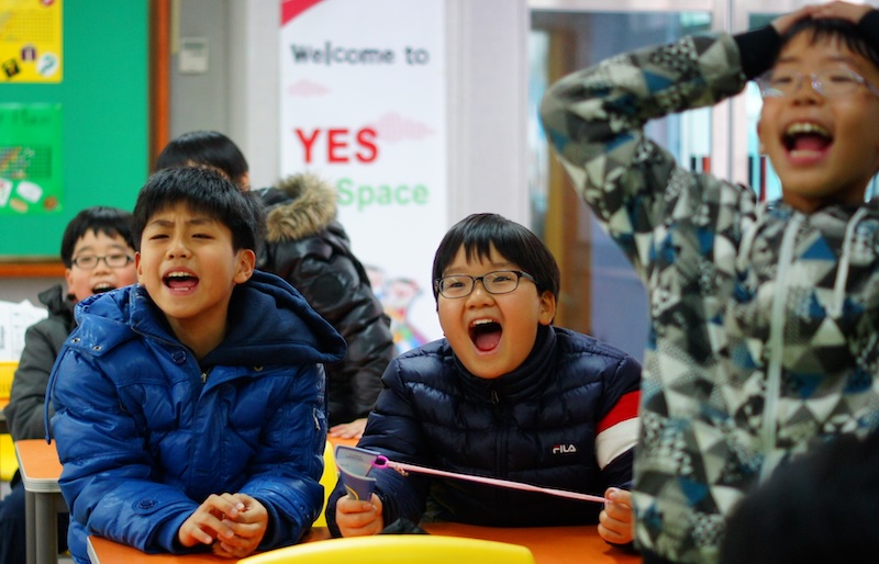 Korean students cheering during a game being played in Elementary school in South Korea 