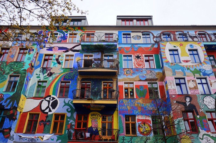 Kreutzigerstrasse in Berlin, Germany, featuring brightly painted residential buildings covered in colorful murals, rainbows, and creative street art designs, making it one of the city’s most vibrant and photogenic streets
