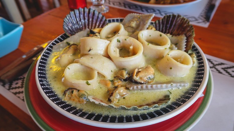 Delicious seafood dish served at La Covacha restaurant in Puerto Pirámides, Península Valdés, Argentina, featuring tender calamari rings, mussels, scallops, and clams in a creamy garlic and herb sauce — a must-try Patagonian specialty