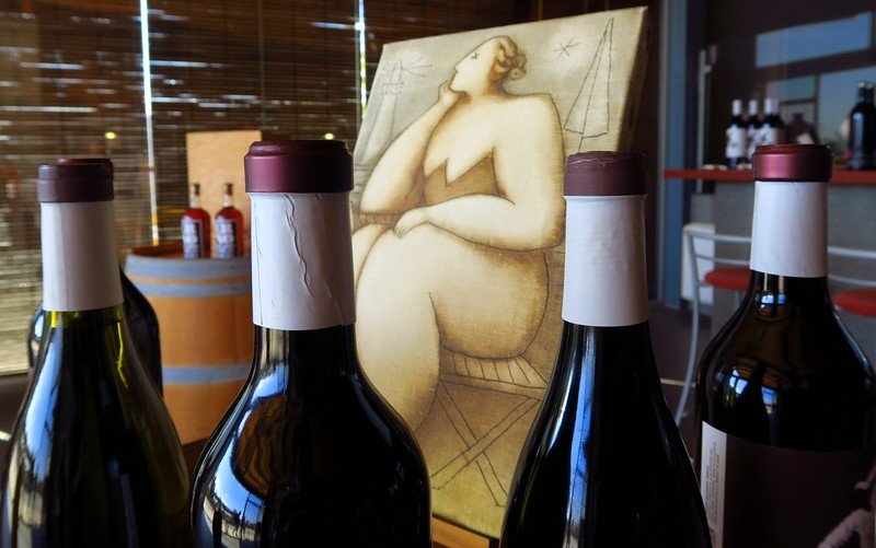 Bottles of wine displayed at La Vinyeta winery in Costa Brava, Spain, with a distinctive piece of local artwork in the background, capturing the blend of Catalan culture, art, and viticulture that makes this boutique vineyard a unique wine destination