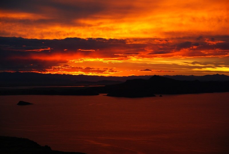 Lake Titicaca fire-y red sunset in Peru with landscape silhouettes 