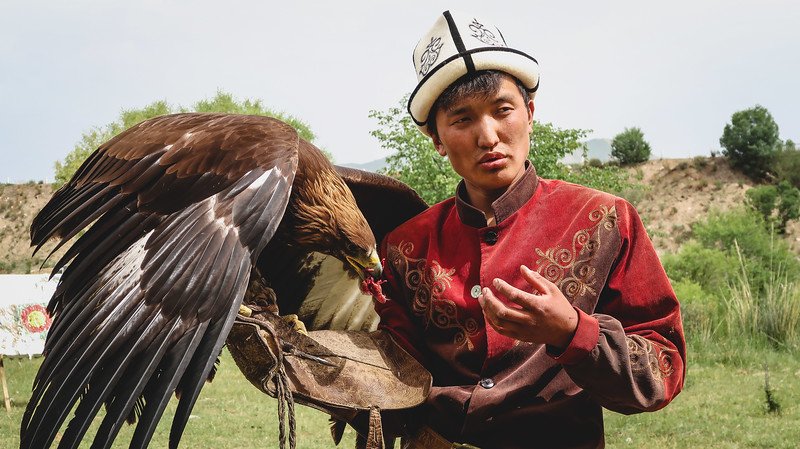 Learning about the tradition of hunting with golden eagles in Kyrgyzstan from locals wearing traditional attire 