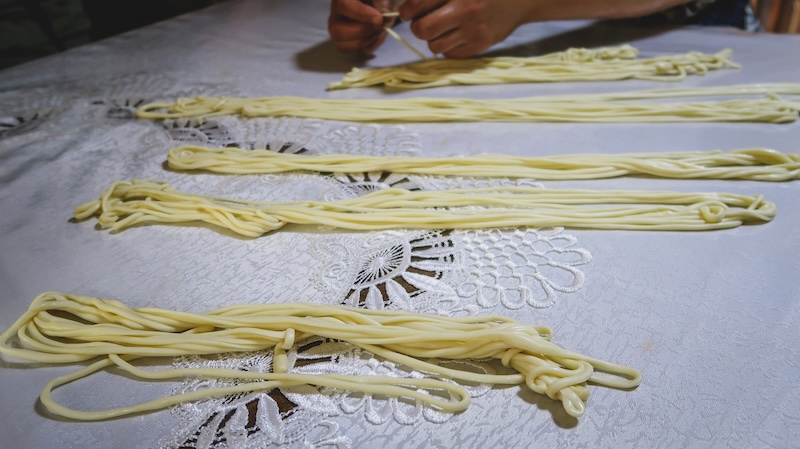 Learning to make noodles in Karakol, Kyrgyzstan forming them into bundles on the table 