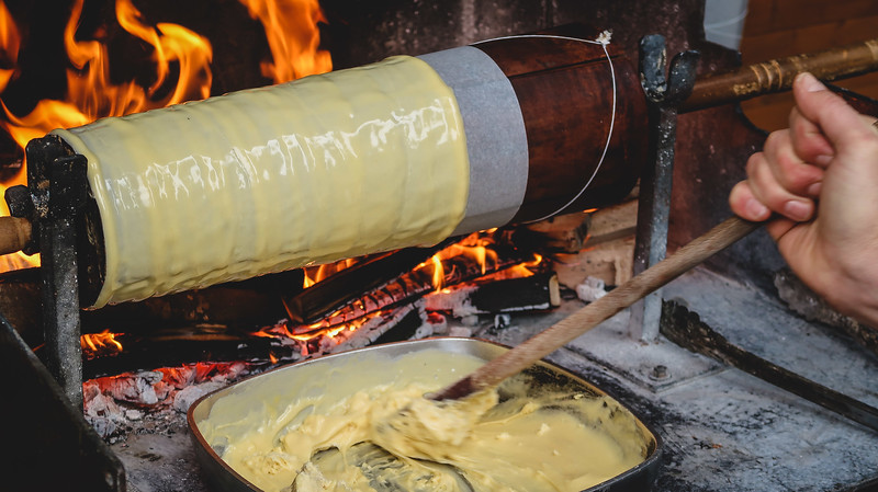 Learning to make Prügeltorte in Tyrol the old fashioned way over a fire with turning wheel and batter mixed in a pan in Austria 