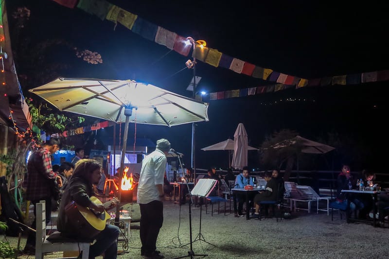 Live music in Pokhara at night with a fire pit and guests gathered in plastic chairs 