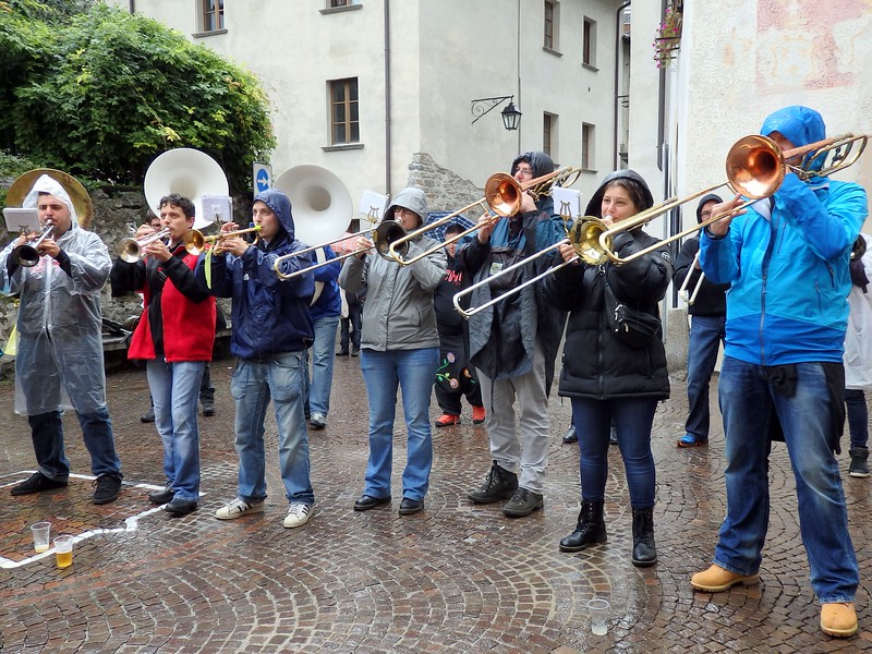 Live music in the town square in Chiavenna, Italy with performers entertaining the crowds using a wide range of instruments in the rain with gusto 
