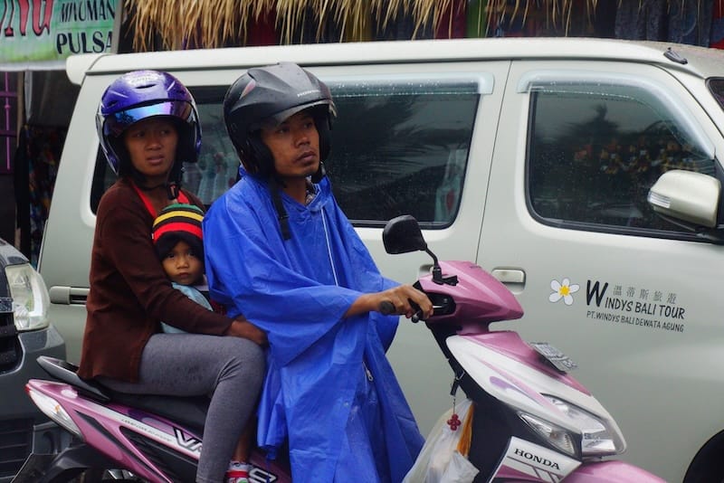 Local family of three on a scooter in Bali, Indonesia 