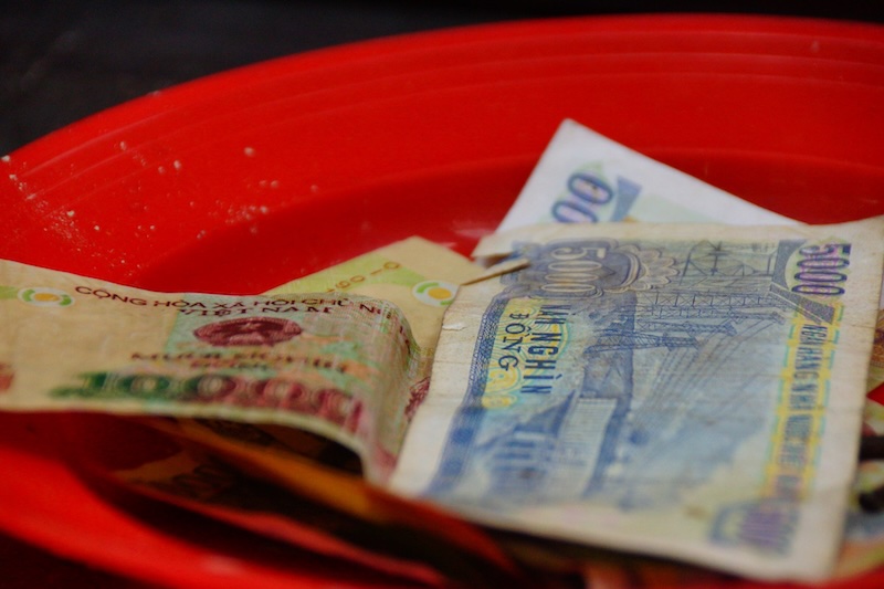 Local Vietnamese currency spread out in all directions in a red bowl Local Vietnamese currency spread out in all directions in a red bowl