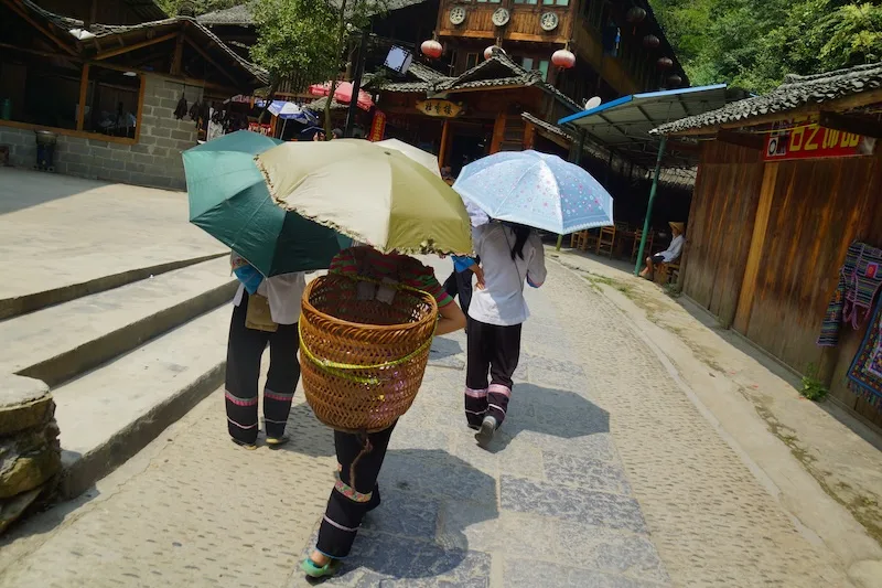 Local wearing sun umbrellas and wicker baskets in China