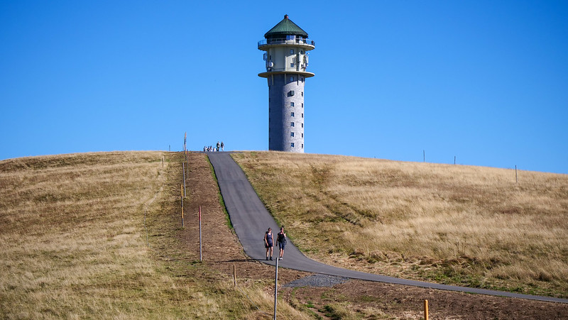 Lookout tower atop Feldberg, the highest peak in the Black Forest with tourists walking on the well defined path 