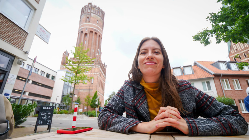 Lunch with a restaurant view of the water tower in Lüneburg with That Backpacker Audrey Bergner grinning yet hungry in Germany