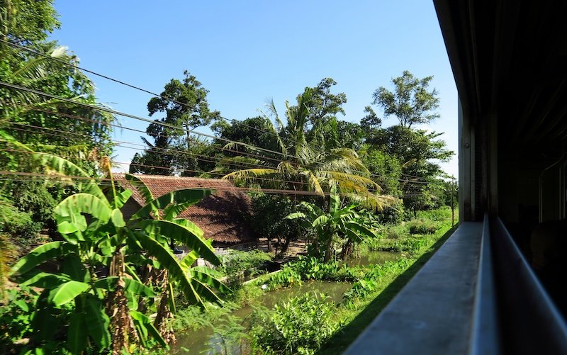 Lush rural views and simple homes outside the train window in Indonesia 