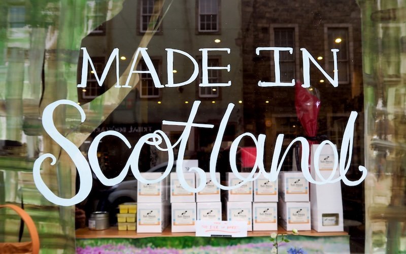 Shop window in Edinburgh displaying Made in Scotland sign with shelves of local food products and gifts featured on Eat Walk Edinburgh food tour