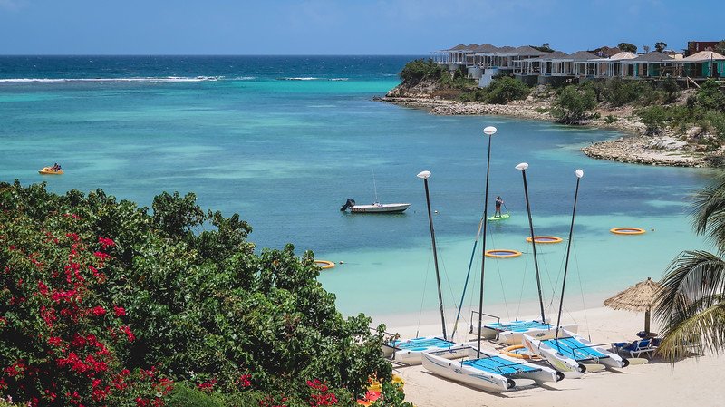 Main beach at Verandah Resort and Spa in Antigua with catamarans, beach huts and stand up paddle-boarding Main beach at Verandah Resort and Spa in Antigua with catamarans, beach huts and stand up paddle-boarding