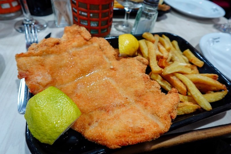 Milanesa con papas fritas aka breaded cutlet with fries is a classic Argentine meal in Buenos Aires, Argentina 