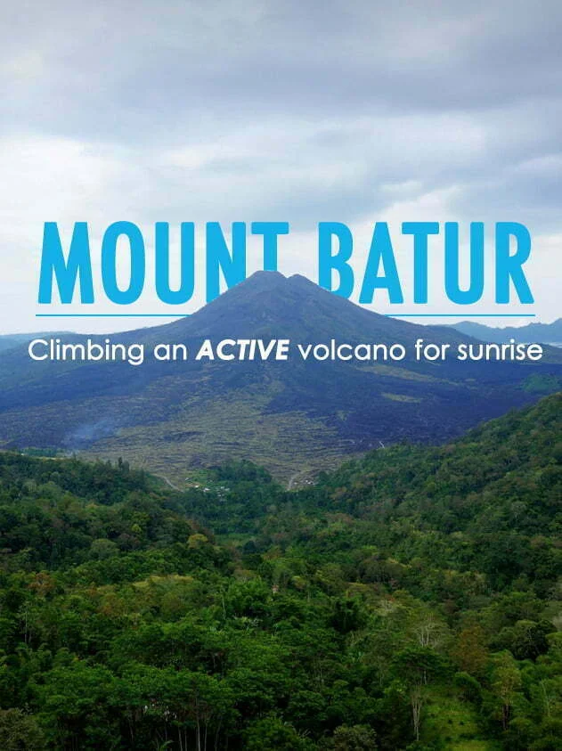 Panoramic view of Mount Batur in Bali, Indonesia, rising above lush green forests under cloudy skies, with text overlay reading “Mount Batur: Climbing an Active Volcano for Sunrise