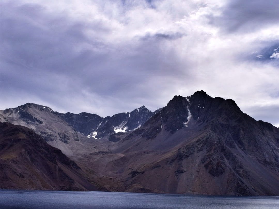Mountain views in Chile with snow capped peaks and moody clouds that can be enjoyed on a day trip from Santiago, Chile