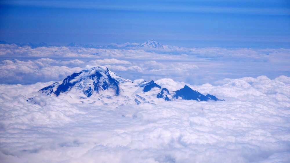 Incredible mountains with ice caps bathed in clouds views flying over Alaska 