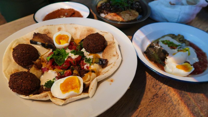 A colourful Middle Eastern-inspired meal with falafel, soft-boiled eggs, roasted vegetables, and creamy sauces served with flatbread at Naschmarkt in Vienna, Austria — a must-visit spot for foodies A colourful Middle Eastern-inspired meal with falafel, soft-boiled eggs, roasted vegetables, and creamy sauces served with flatbread at Naschmarkt in Vienna, Austria — a must-visit spot for foodies
