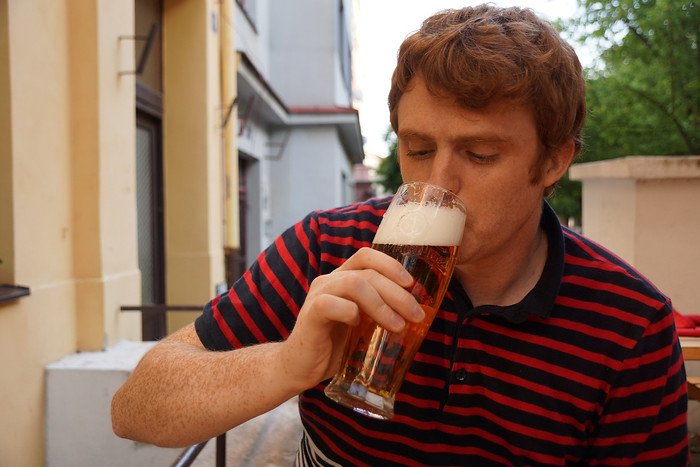 Nomadic Samuel enjoying a freshly poured glass of golden Pilsner beer at an outdoor pub in Prague, Czech Republic, experiencing the city’s famous beer culture