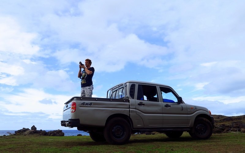 Nomadic Samuel taking photos from the back of a pickup truck on Easter Island (Rapa Nui), capturing dramatic coastal landscapes