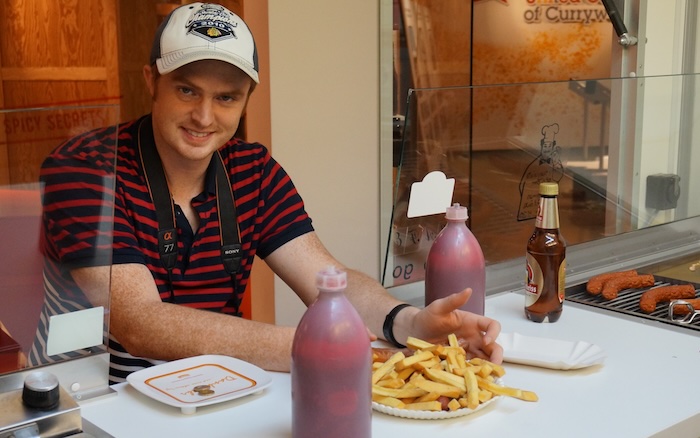 Nomadic Samuel eating currywurst in Berlin, Germany 