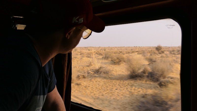 Nomadic Samuel enjoying desert views of Rajasthan from the train window riding an Indian train Nomadic Samuel enjoying desert views of Rajasthan from the train window riding an Indian train