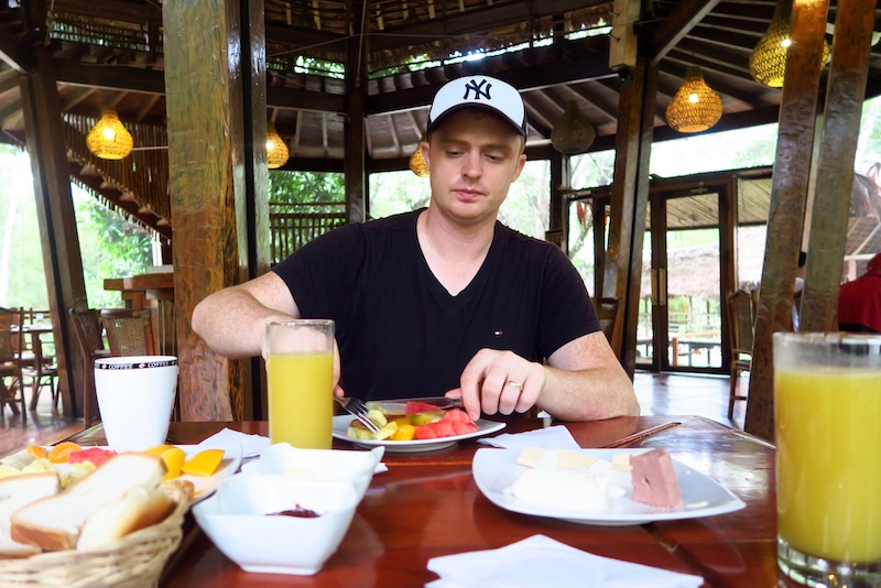 Nomadic Samuel enjoying tropical fruits for breakfast at the treehouses lodge in the Amazon jungle of Peru 