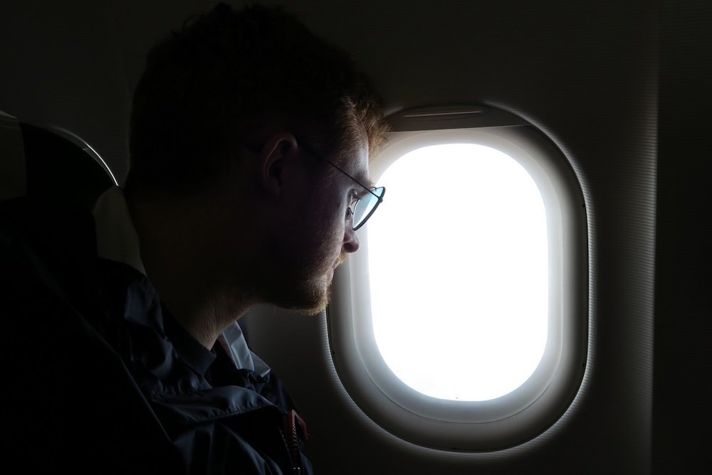 Nomadic Samuel looking outside of the window from the airplane mid air 