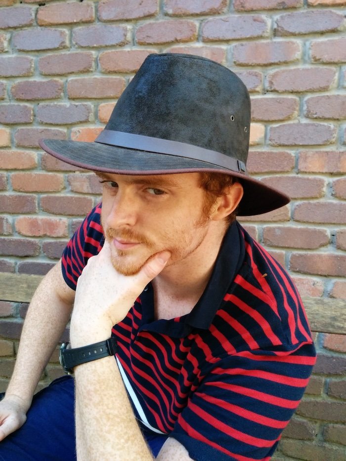 Nomadic Samuel wearing a new wide-brimmed outback hat and striking a thoughtful pose against a brick wall during a visit to Currumbin Wildlife Sanctuary on the Gold Coast, Australia