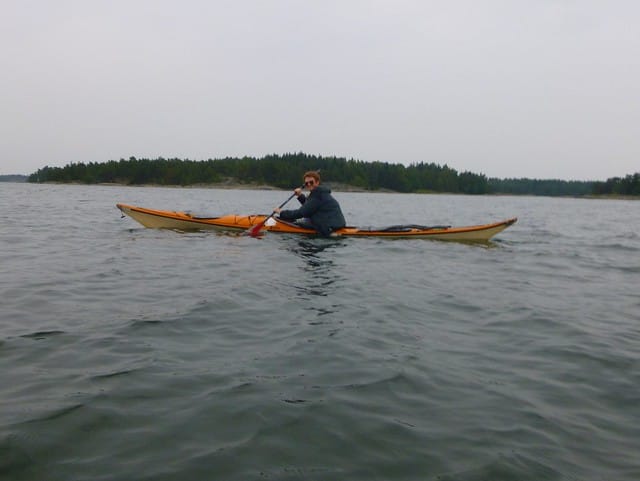 Nomadic Samuel Sam sea kayaking in the Archipelago Sea in Finland with a smile on his face enjoying the adventure outdoors  