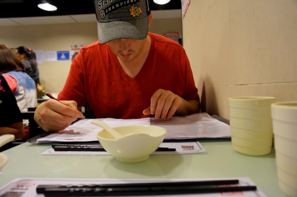 Nomadic Samuel studying a menu in Hong Kong 