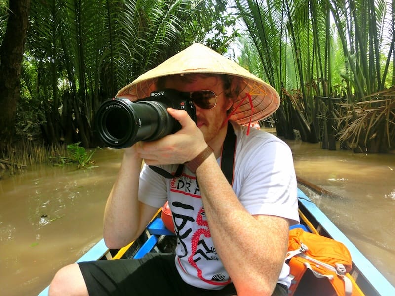 Nomadic Samuel taking photos with a telephoto lens on the Mekong Delta Tour in Vietnam 