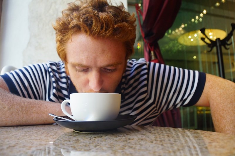 Nomadic Samuel enjoying a hot drink at a café in Tallinn, Estonia during a day trip from Helsinki