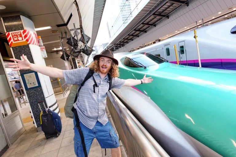 Nomadic Samuel wearing shorts and a t-shirt boarding the Shinkansen in Japan Nomadic Samuel wearing shorts and a t-shirt boarding the Shinkansen in Japan