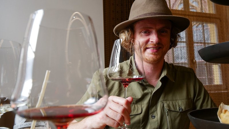 Nomadic Samuel enjoying a red wine tasting experience at Alte Wache wine bar in Freiburg im Breisgau, Germany, with glasses of local wine in the foreground