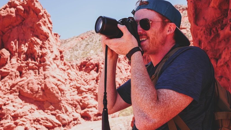 Nomadic Samuel with hat, sunglasses and camera capturing the magic of Jujuy on a day trip from Salta, Argentina 