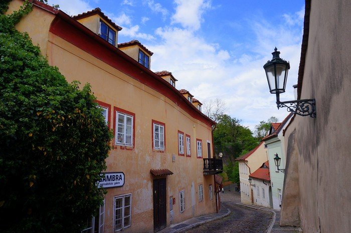 Charming cobblestone lane lined with pastel historic houses and vintage lanterns in the quiet Nový Svět neighbourhood near Prague Castle in Prague, Czech Republic, on a sunny afternoon