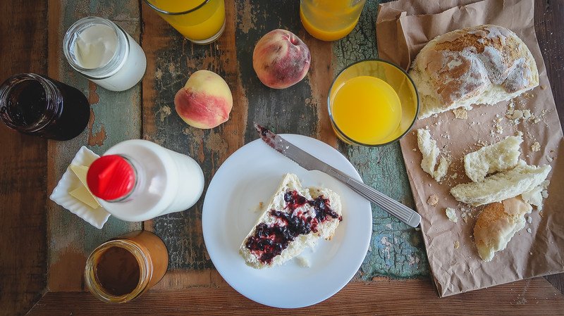 Homemade breakfast spread at Oceano Patagonia eco hotel in Puerto Pirámides, Península Valdés, Argentina, featuring crusty bread with jam, fresh peaches, orange juice, local milk, yogurt, and dulce de leche — a rustic Patagonian morning meal