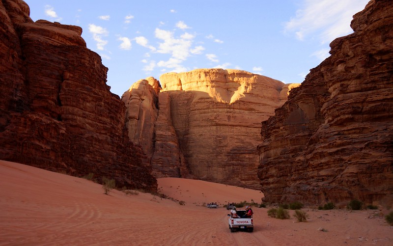Off-roading between massive rock formations in Wadi Rum, Jordan with harsh contrast between illuminated and shaded sections 