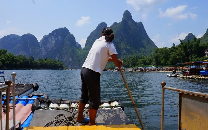 Our captain on Li river cruise punting the boat out of the loading dock in China