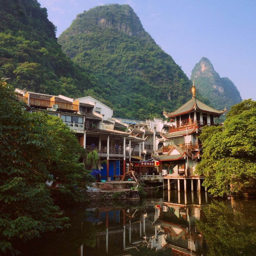 Pagoda by the lake with stilt buildings in China with beautiful karst mountain views as a backdrop creating an epic stunning scene