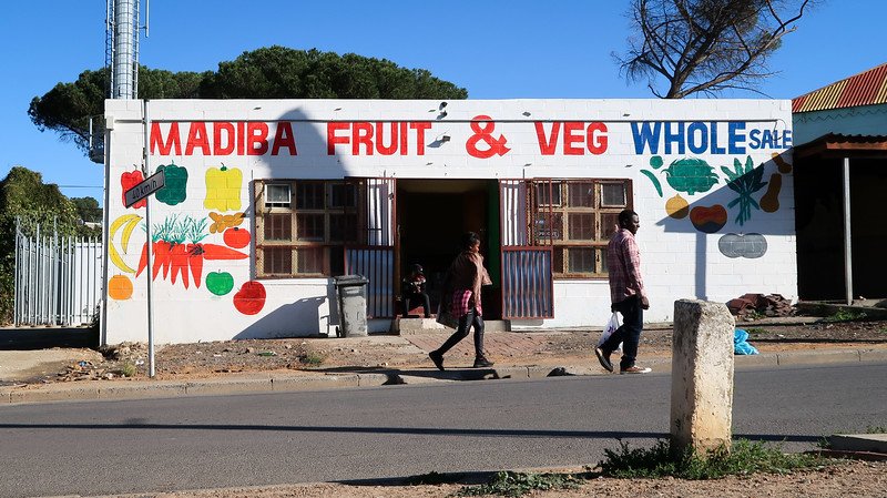 Painted buildings in Kayamandi such as this one with Madiba Fruit & Veg wholesale with fruit and veggies painted on the white exterior 