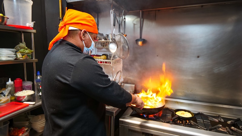 Peruvian cuisine being prepared by a local chef on the wok with fire in Miraflores, Lima, Peru 