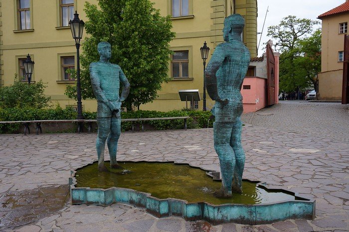 Quirky bronze kinetic sculpture Piss by David Černý depicting two men urinating into a map-shaped basin, located outside the Kafka Museum in Prague, Czech Republic