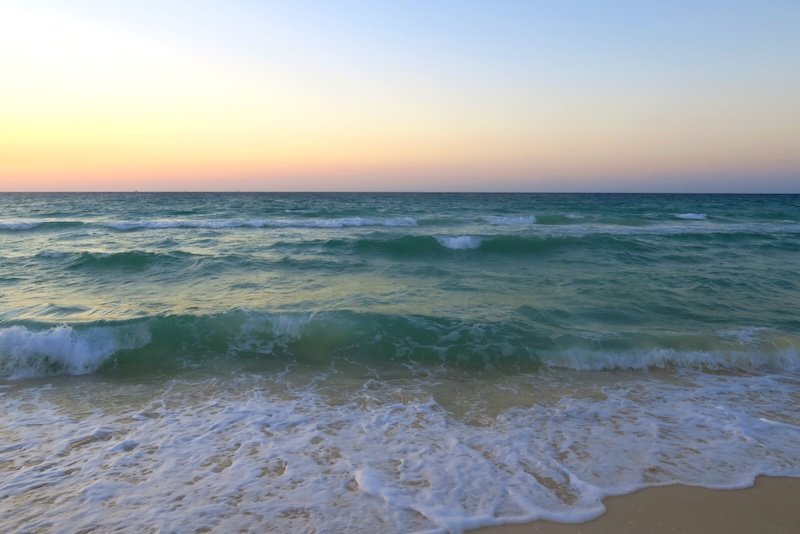 Waves rolling onto the sandy shore in Playa del Carmen at twilight, with soft pastel skies blending into the turquoise Caribbean Sea Waves rolling onto the sandy shore in Playa del Carmen at twilight, with soft pastel skies blending into the turquoise Caribbean Sea