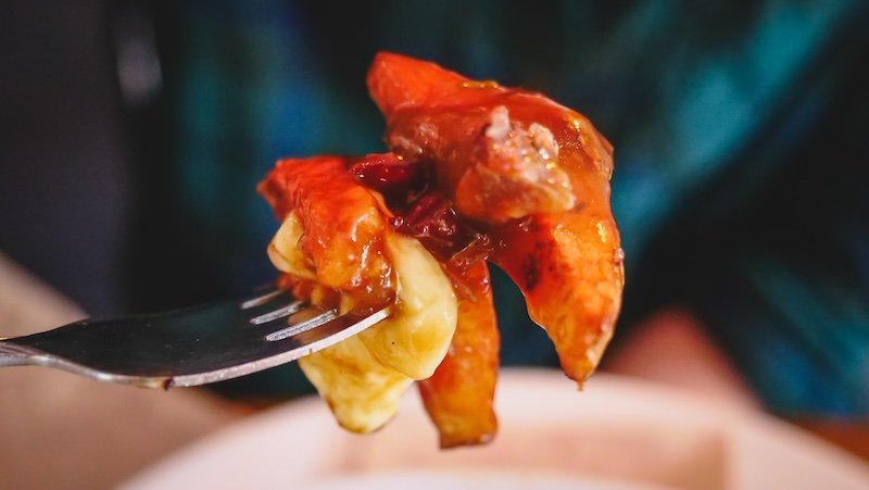 Close-up of a forkful of gooey poutine with melty cheese curds, rich gravy, and crispy fries at a cozy eatery in Sutton, Quebec’s Eastern Townships.