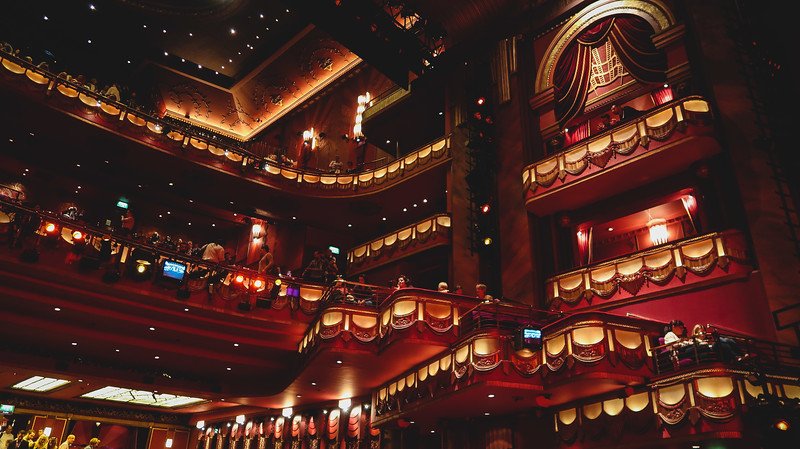The ornate interior of the Prince Edward Theatre in London, with its glowing balconies, velvet curtains, and golden details, captures the elegance and grandeur of the West End, where audiences gather for world-class musicals and live performances
