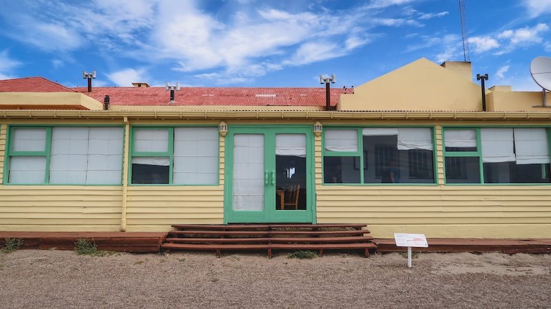 Colorful guesthouse with yellow walls, green-trimmed windows, and a red roof in Puerto Pirámides, the small village on Peninsula Valdés in Patagonia, Argentina, where many travelers stay overnight to explore the UNESCO wildlife reserve